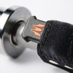 Close-up of a motorcycle handlebar grip with Enode Replacement Barbell Strap in black and orange attached to the throttle control. The grip has a textured surface, and the strap uses Velcro for secure fastening.